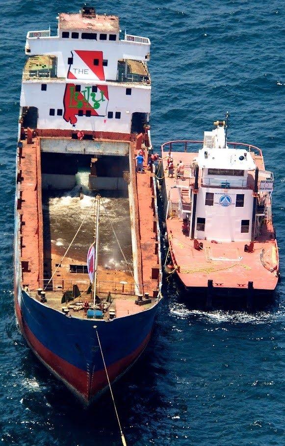 Large vessel with a tugboat alongside before a controlled sinking