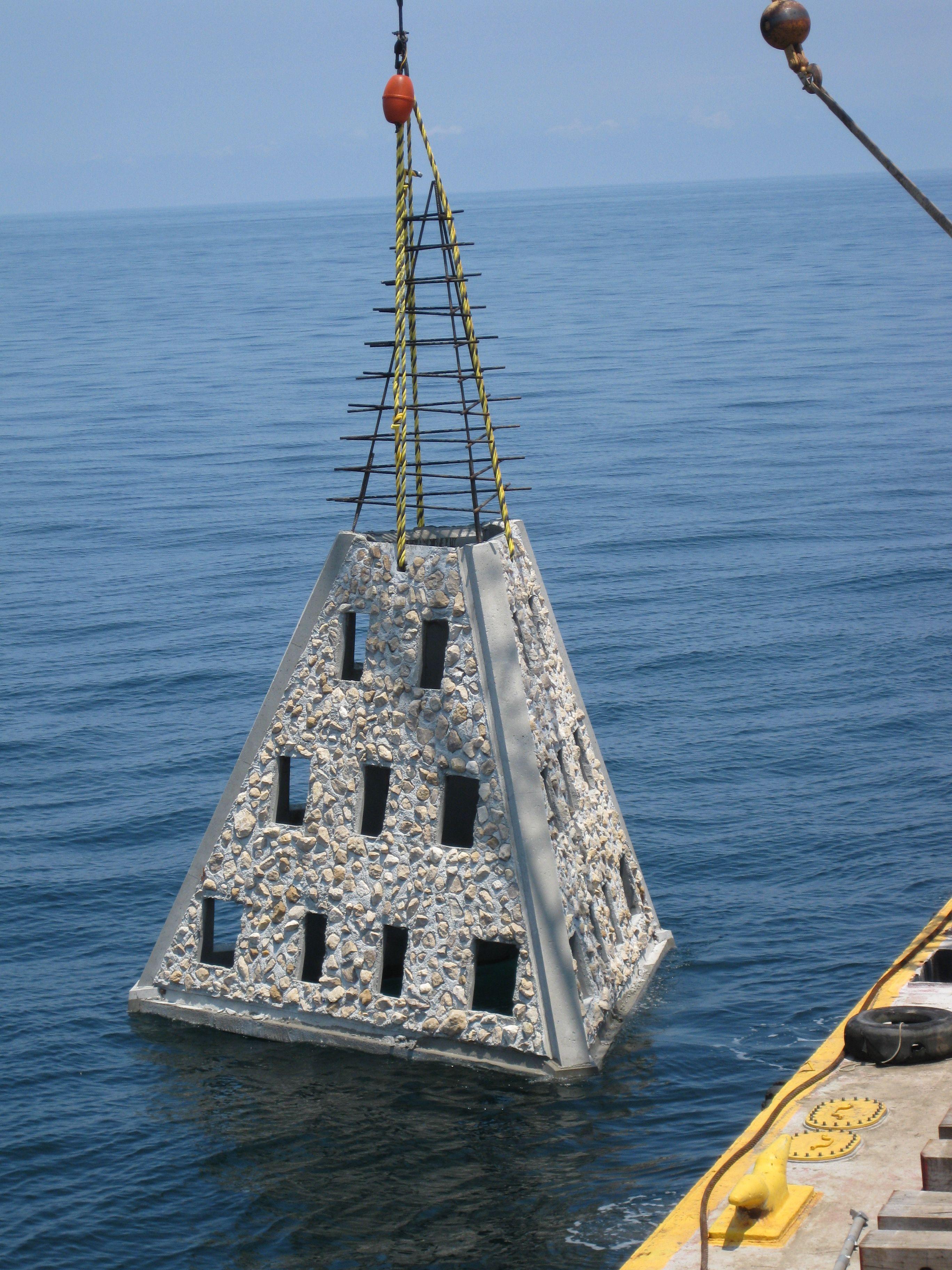 Pyramid-shaped Super Reef module suspended by crane cables above the water