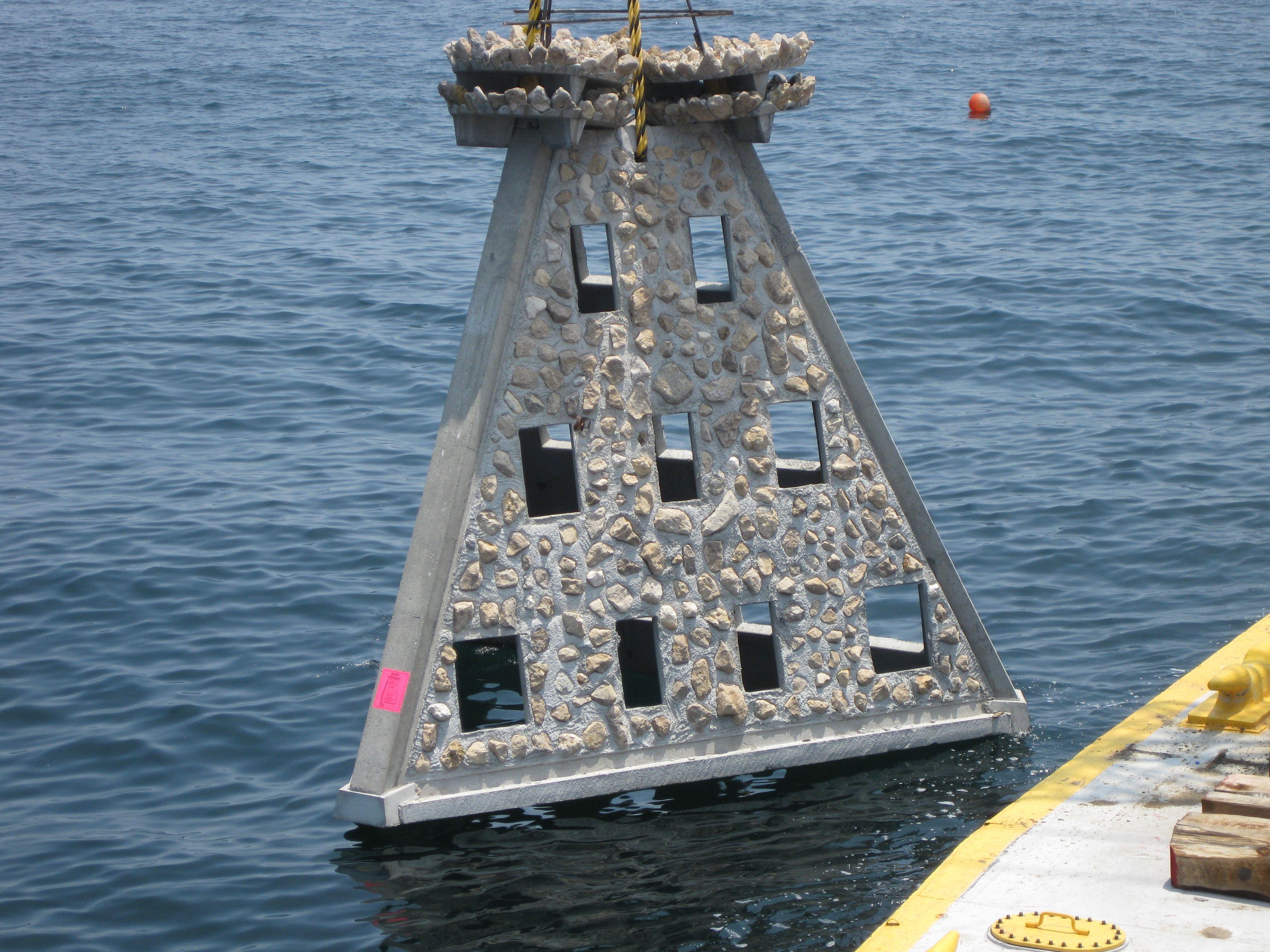 Super Reef artificial reef module being lowered into the water beside a deployment vessel