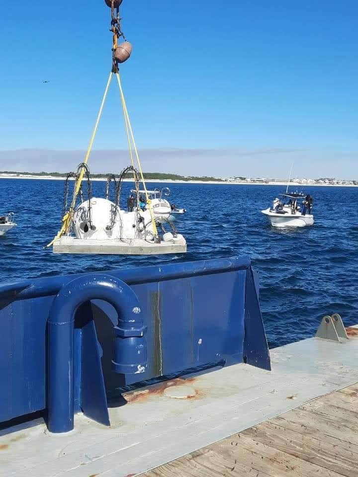 Small artificial reef structure suspended over the sea behind a vessel