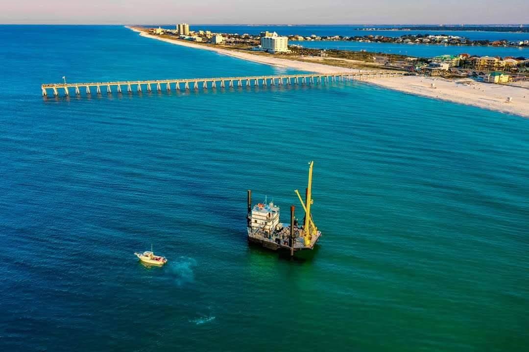 Artificial reef structure suspended in turquoise water near a pier