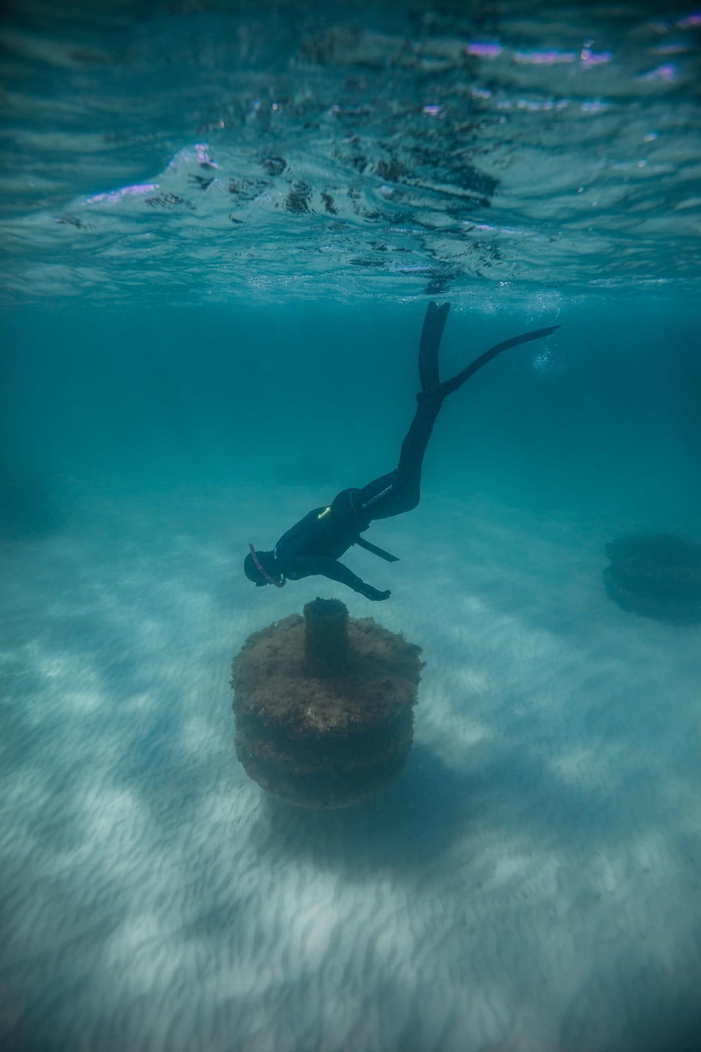 Diver descending toward a round artificial reef habitat