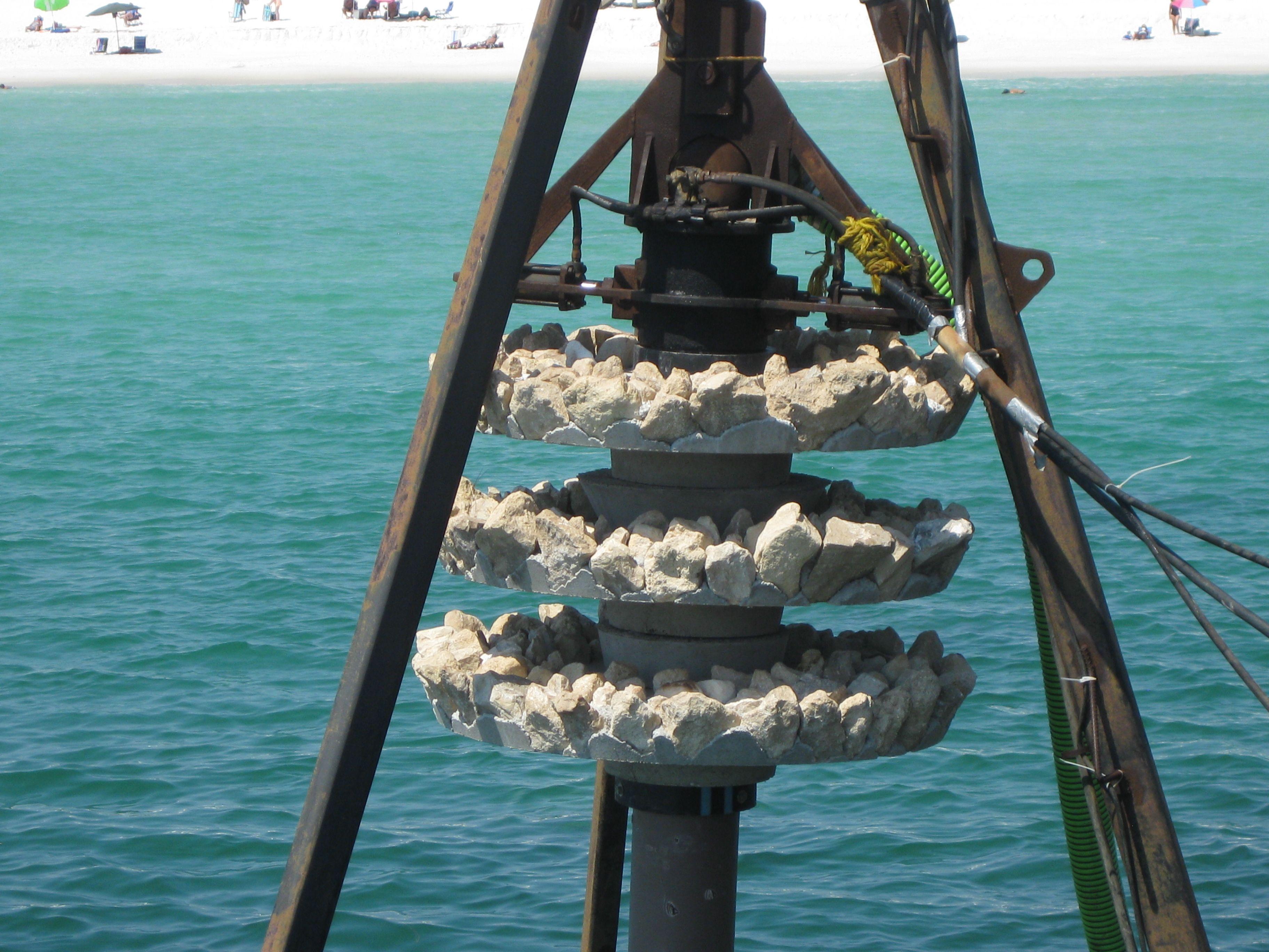 Stacked shell-covered reef habitat discs suspended above the water