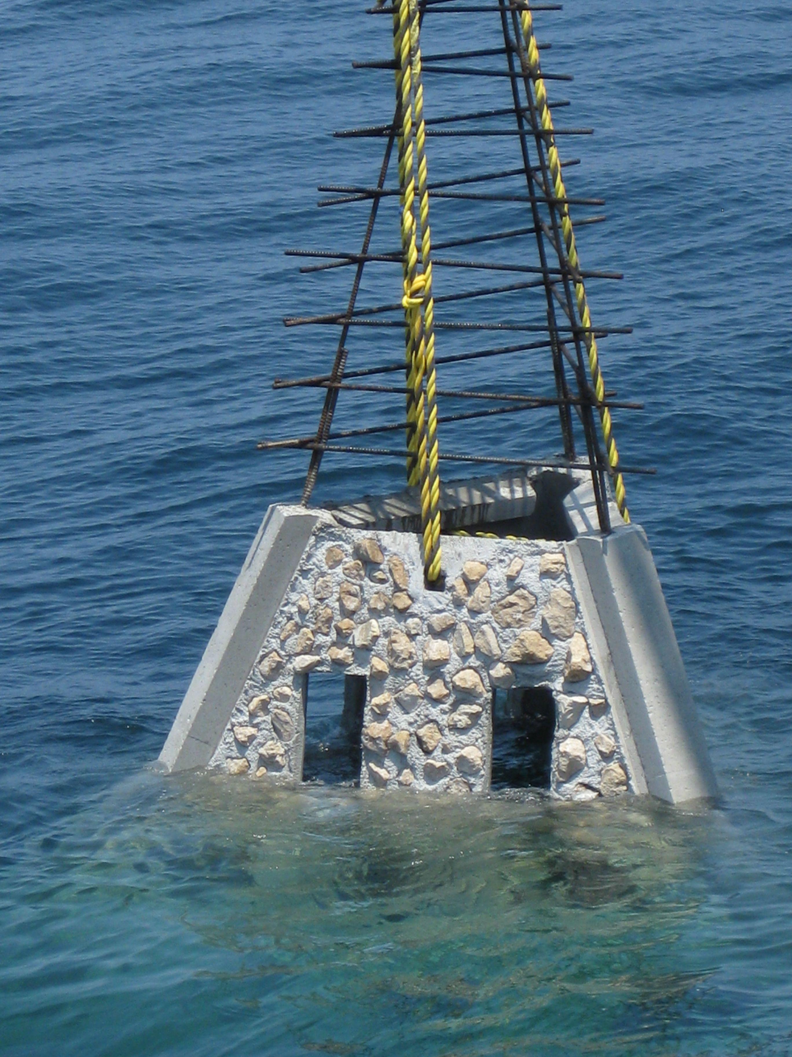 Pyramid-shaped concrete reef module being lowered into the sea