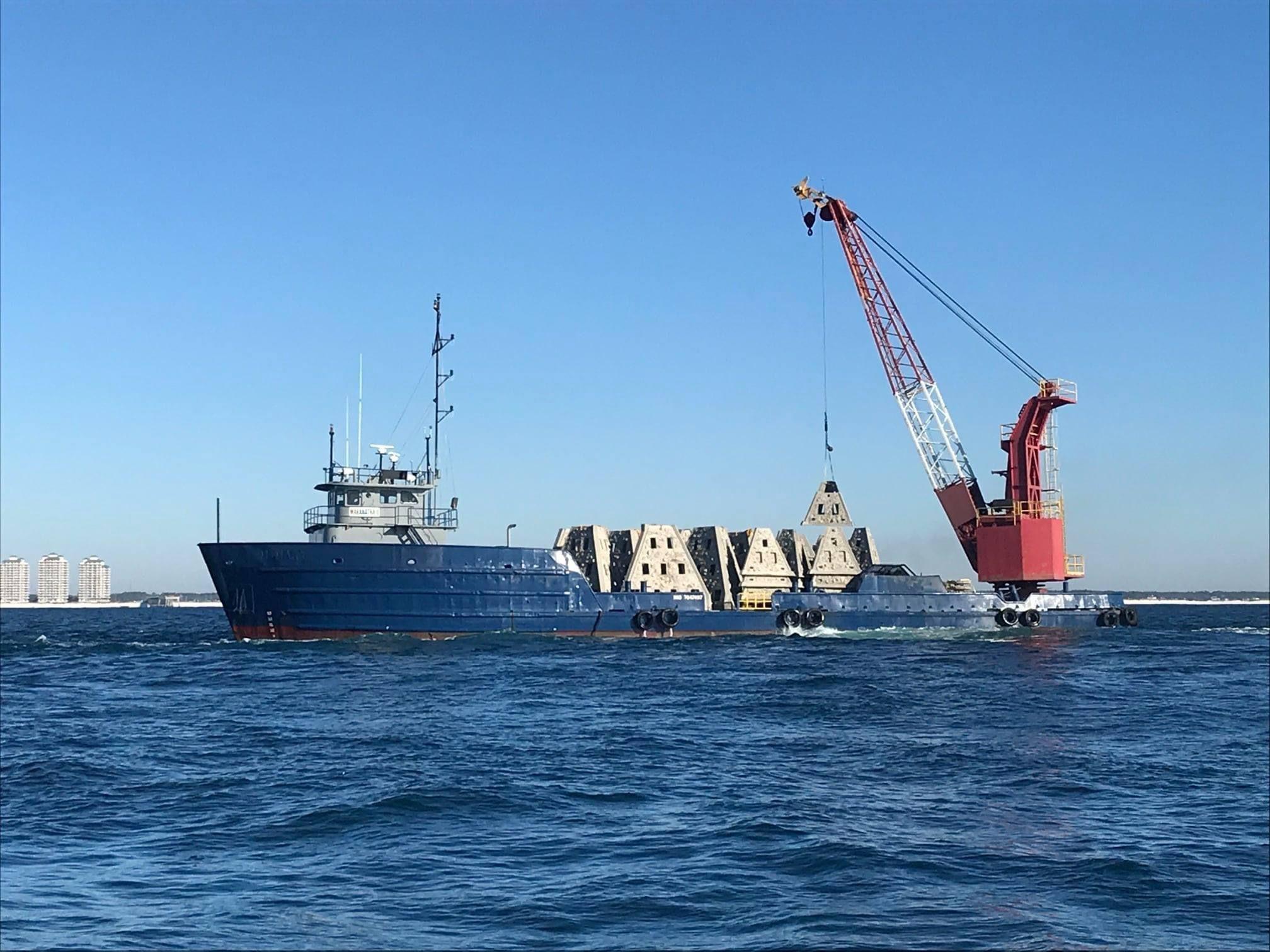 Crane vessel transporting pyramid artificial reef modules offshore